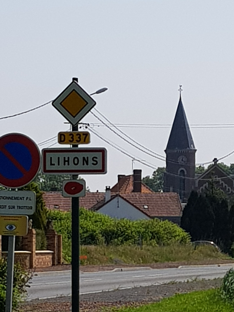A road sign in front of a church tower in a small village.