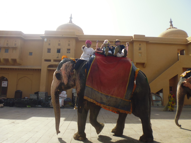 People riding an elephant in front of a historical building.