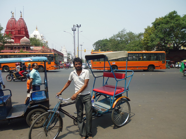 Street scene in India with a man holding a rickshaw.
