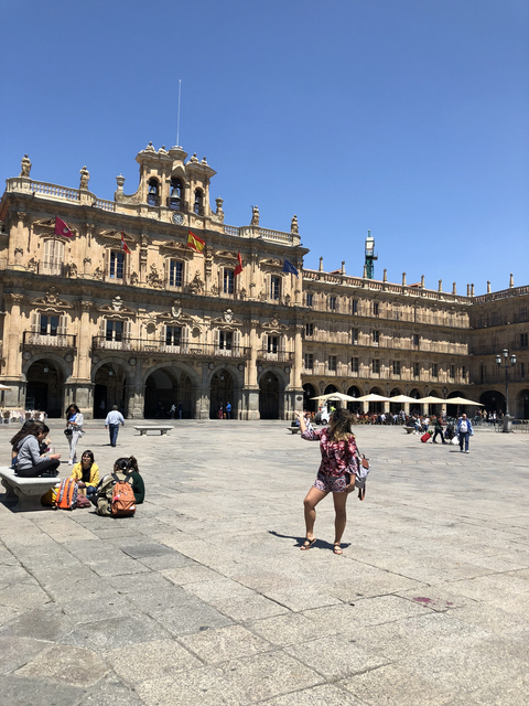 People enjoying a sunny day in a historic European plaza.