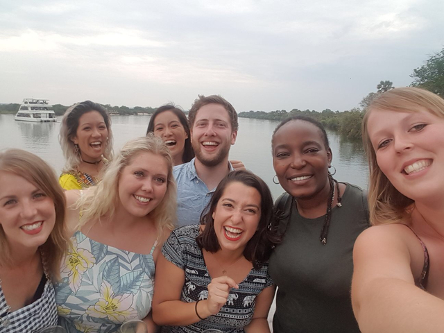 Group of people taking a selfie on a boat with a river background.