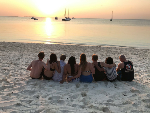 Group sitting on the beach at sunset.