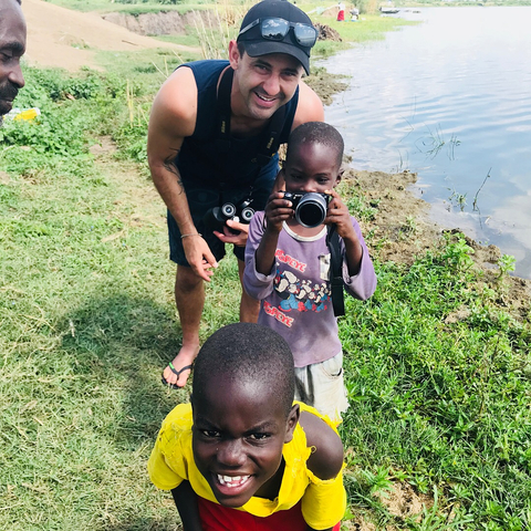 Child taking a photograph near a body of water.