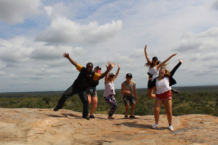 Group of people jumping on rocky terrain.