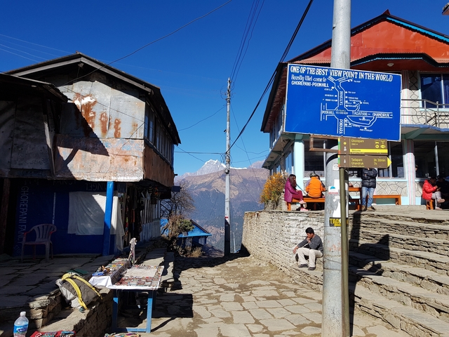 People walking in a mountain village with a view of the Himalayas.