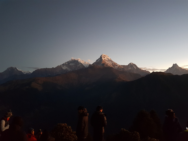 Silhouetted figures in front of the Himalayas at sunset.