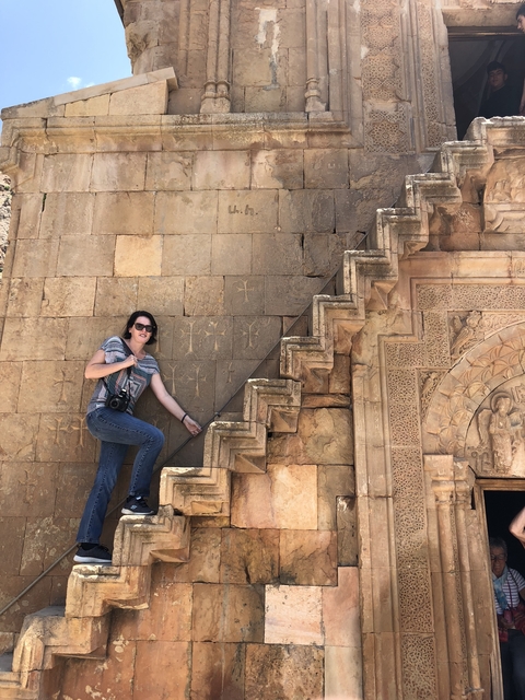       A woman posing on ancient stone stairs with engravings.
  