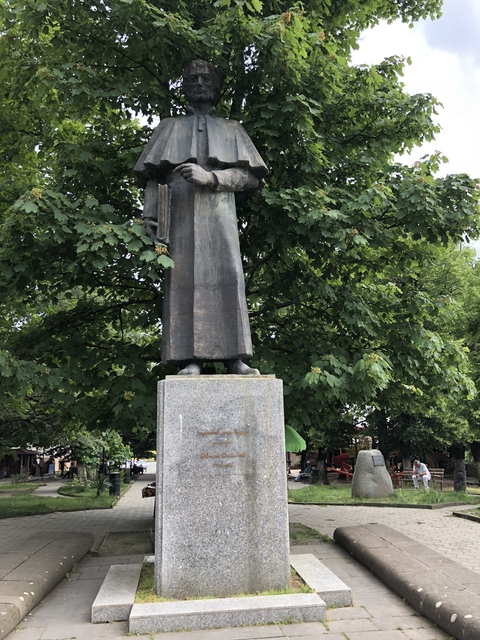       A statue standing among lush green trees.
  
