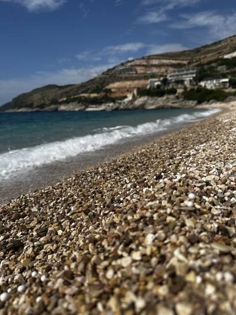 Close-up of a rocky beach shoreline with blue waters.