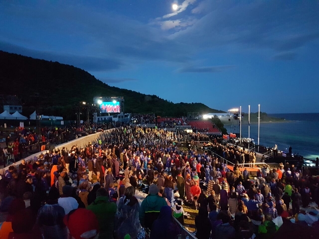       Large crowd gathered at an outdoor event at dusk.
  