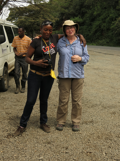 Two travelers posing on a dirt road, one holding a camera.