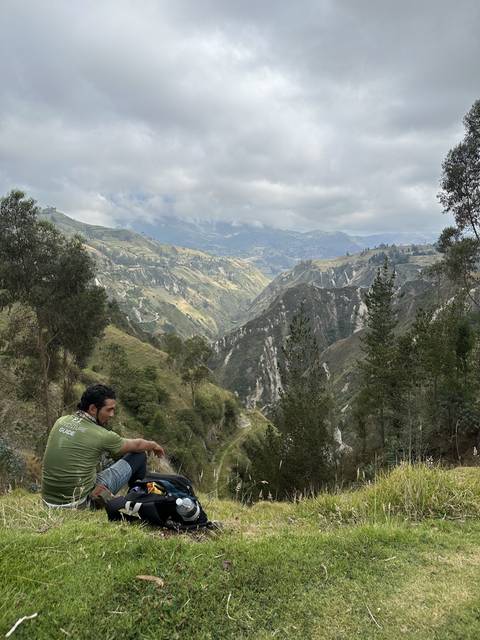 Person resting on a hillside with a view of a valley
