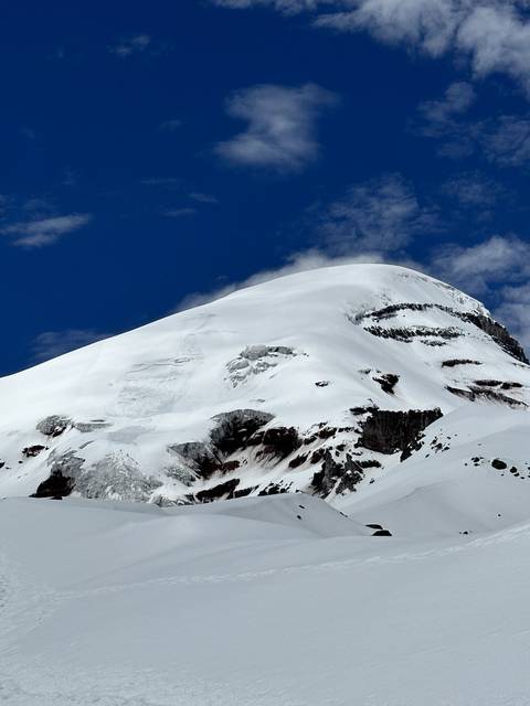 Snowy mountain peak with blue sky and clouds.