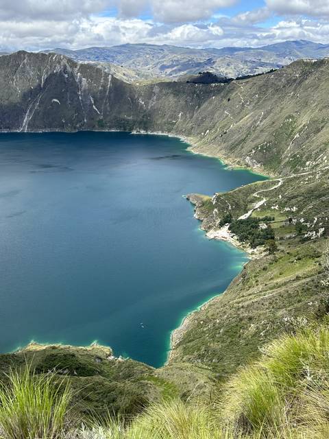 Quilotoa Crater Lake with green and blue waters surrounded by mountains.