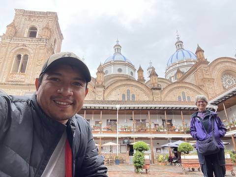 Two people standing in front of a church with blue domes.