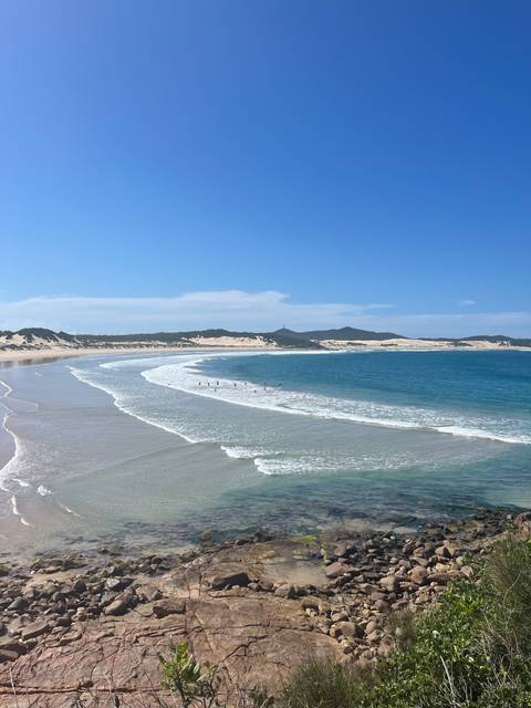 Beach coastline with waves and rocky outcrops.