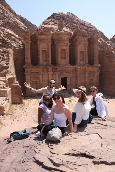       Tourists posing in front of ancient Petra ruins.
  