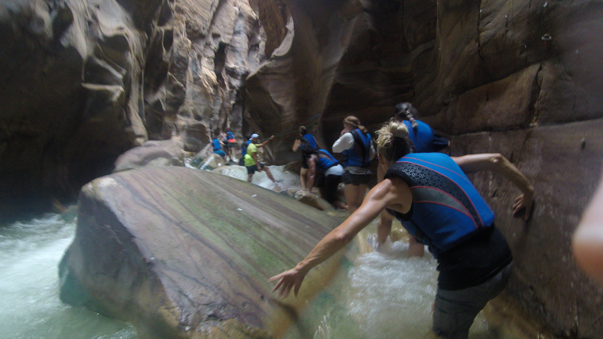       People navigating a narrow canyon with rushing water.
  