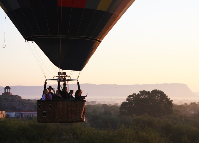 Hot air balloon at sunrise overlooking a landscape.