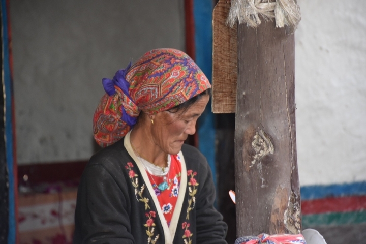       Woman in traditional clothing near a wooden pole.
  