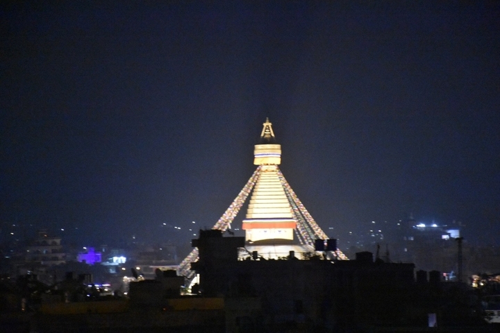      Illuminated stupa at night in a city.
  