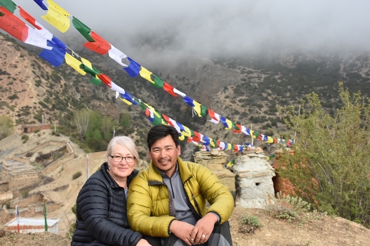 Two people sitting near prayer flags.