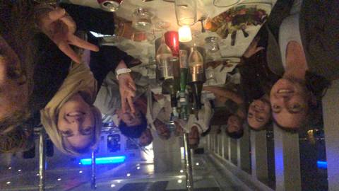       People dining at a table with bottles and glasses.
  