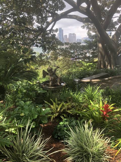       Statue surrounded by greenery with city in distance
  