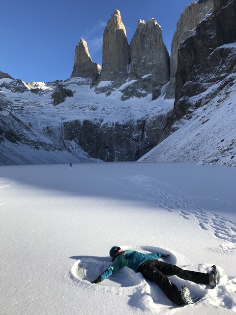       A lone figure walking across a snowy expanse with snow-covered cliffs.
  