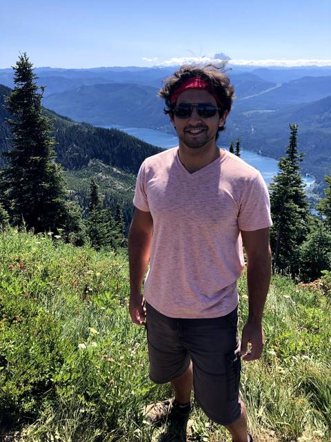      Person standing on a grassy mountain slope.
  