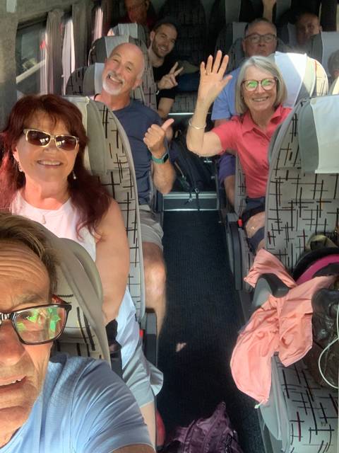 People sitting inside a bus smiling and waving