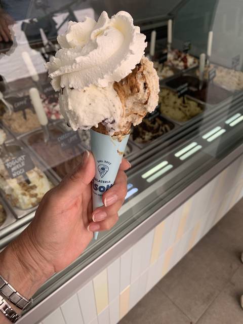       Ice cream cone being held indoors.
  