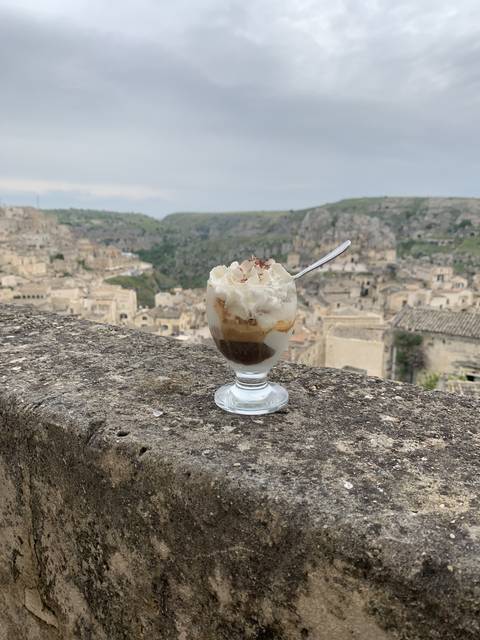 Dessert glass on a stone ledge overlooking a city.