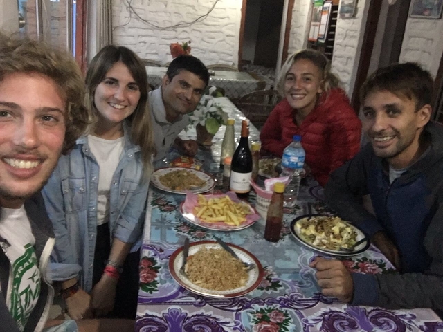 Group of people sitting around a table enjoying a meal in an indoor setting.