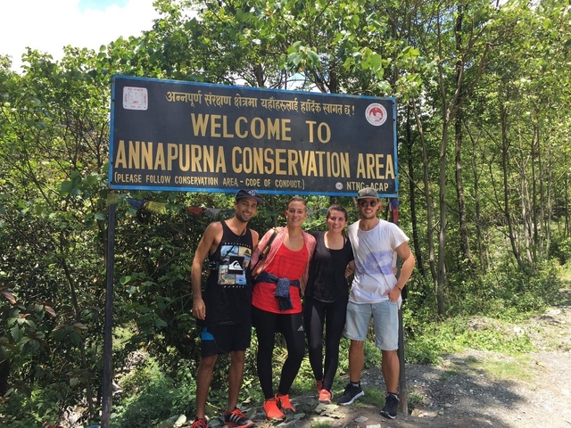 Group of people standing in front of a sign for Annapurna Conservation Area.