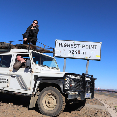 4x4 vehicle at the highest point with people posing on and around it.