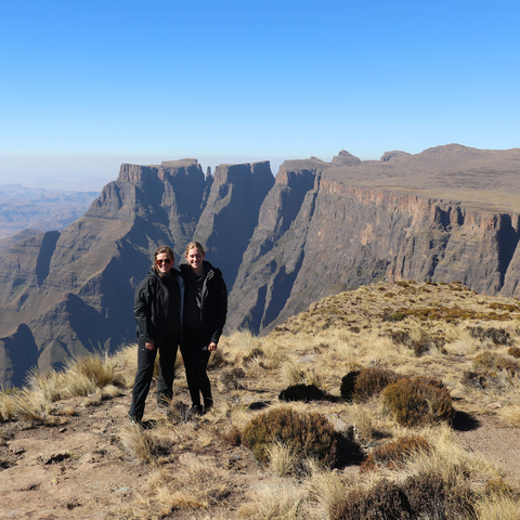 Two people posing at the edge of a cliff with expansive views.
