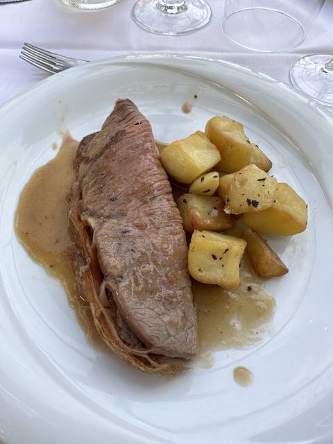       Plate of cooked meat with potatoes.
  