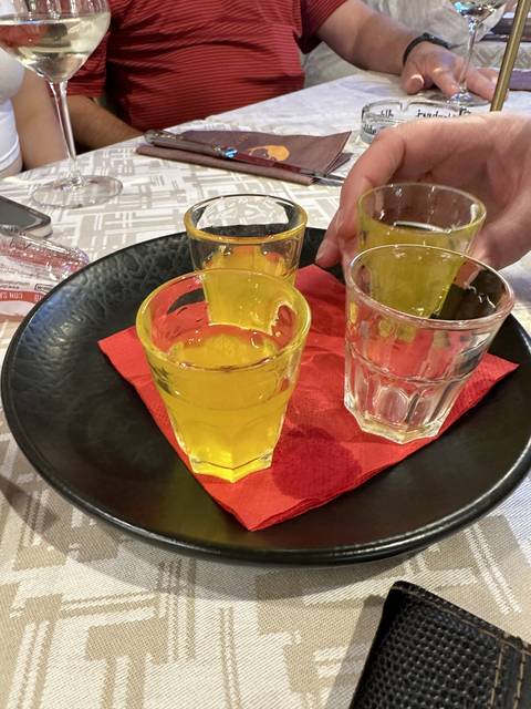       Yellow cocktails on a table with a person's hand.
  