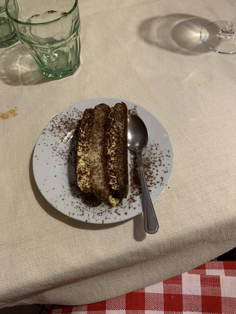Plate with a tiramisu dessert and cutlery on a table.