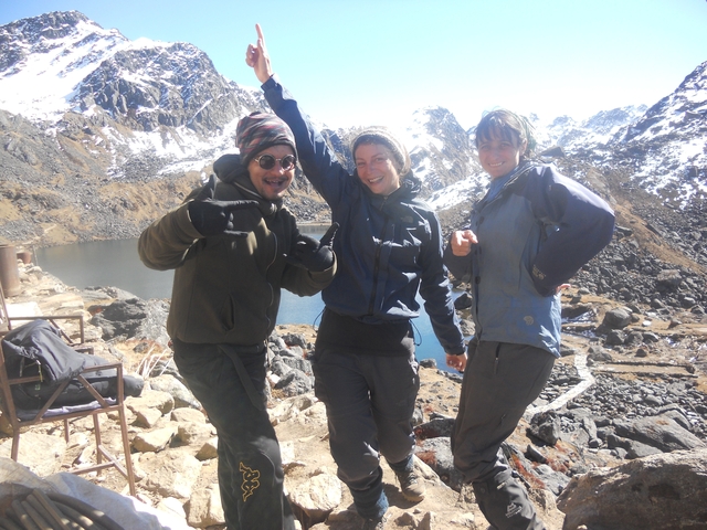 Three hikers posing with a mountain view in the background.