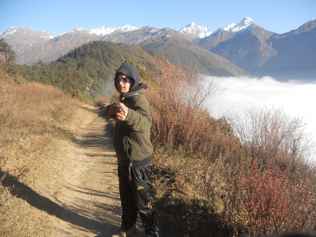 Hiker on a mountain path overlooking a sea of clouds.