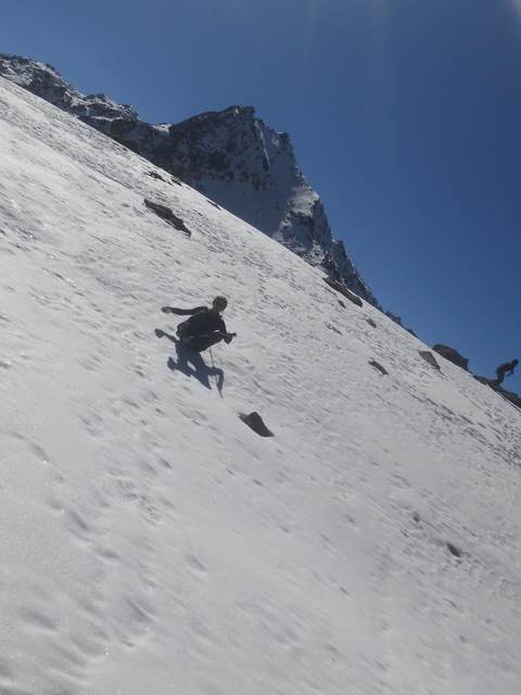 Person sliding down a snowy slope with a stick.