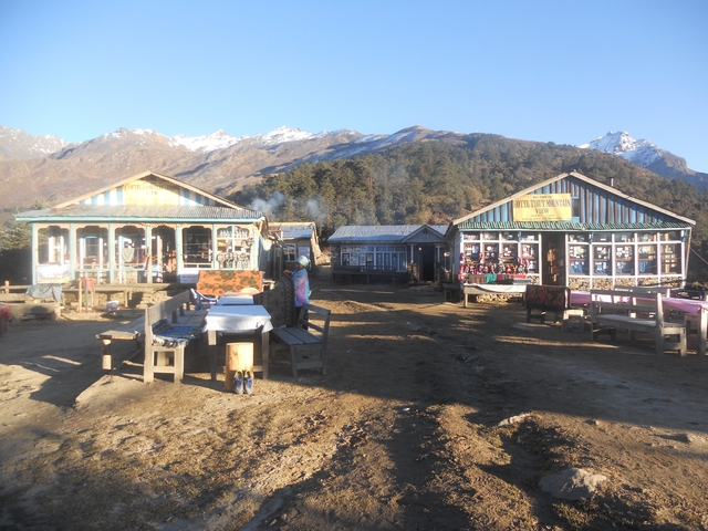 Small mountain village with wooden lodges and snowy peaks.