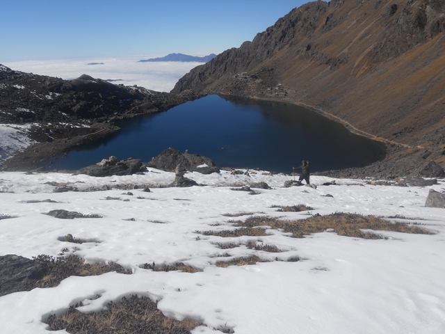 Aerial view of a deep blue mountain lake surrounded by snow.