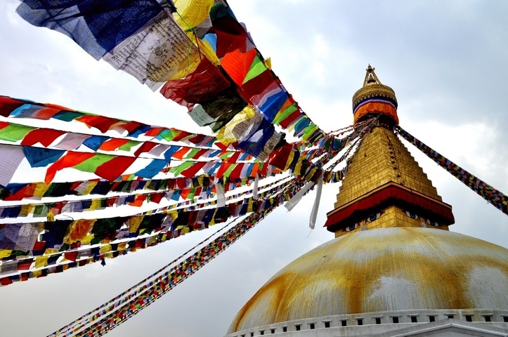      Colorful prayer flags surrounding a golden stupa.
  