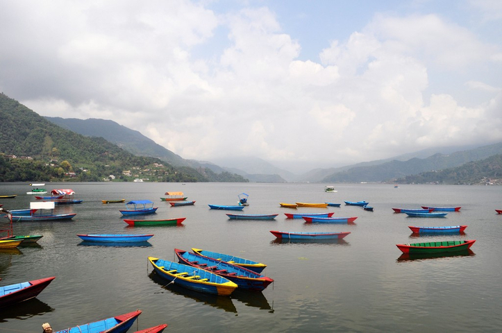       Colorful boats on a lake surrounded by green hills.
  