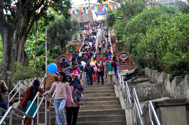       Crowded staircase leading to a temple with many people ascending.
  