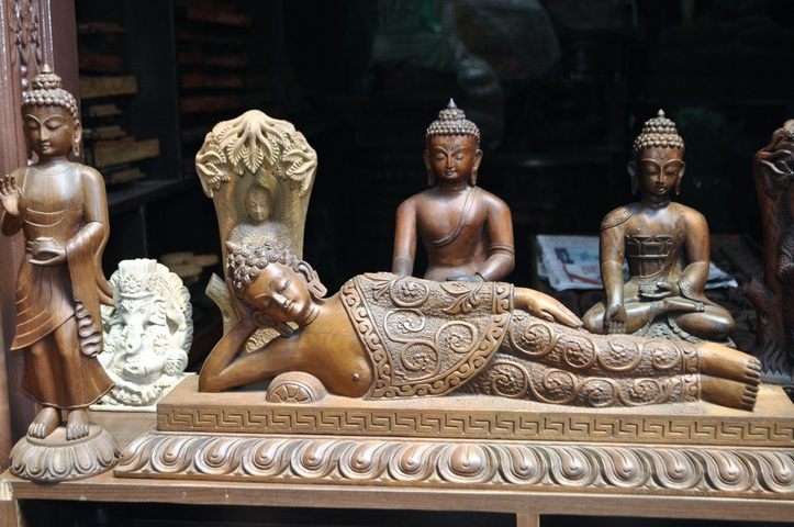       Wooden sculptures of deities and a reclining Buddha.
  