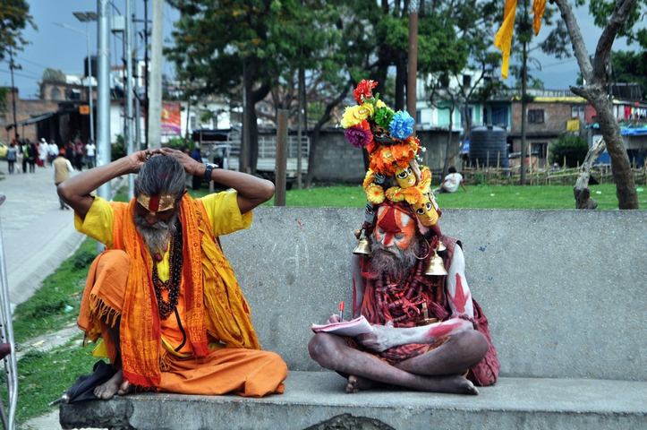       Two people in traditional attire seated, one with flowers.
  